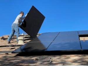Fachkraft montiert Photovoltaikmodule auf einem Hausdach