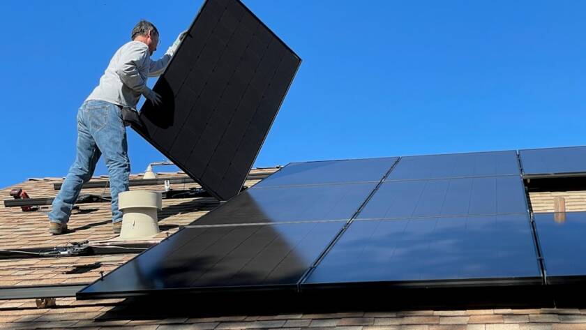 Fachkraft montiert Photovoltaikmodule auf einem Hausdach